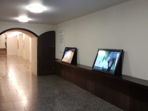 A photograph showing a corridor in the Tate. Along the side of the corridor are large touch screens, where visitors can 'flip through' digitised sketchbooks and art works.
