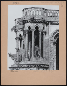 Image of a black and white photograph mounted on cardboard. The photograph shows a detail of the oxen coming through the arches.