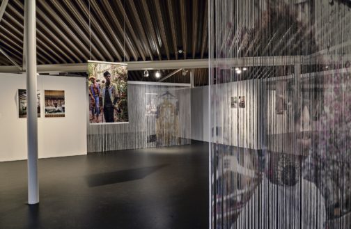 Image of gallery interior with photos hanging from ceiling and on walls
