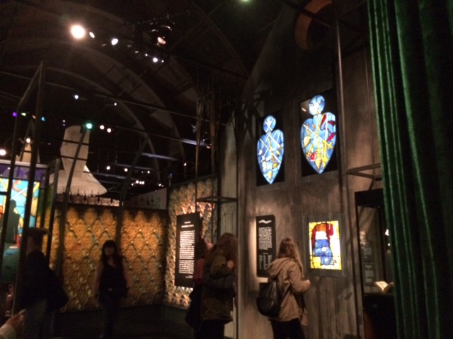Tim Walker exhibition room with large church like wall with three stained glass pieces.