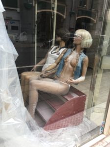 A photograph of two mannequins inside a window shop display