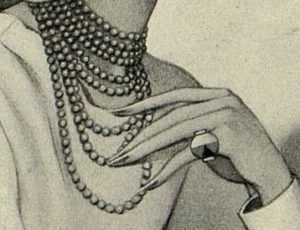 A detail of a 1920s black and white fashion drawing of a woman with long fingernails and a large ring touching her multiple strand pearl necklace.