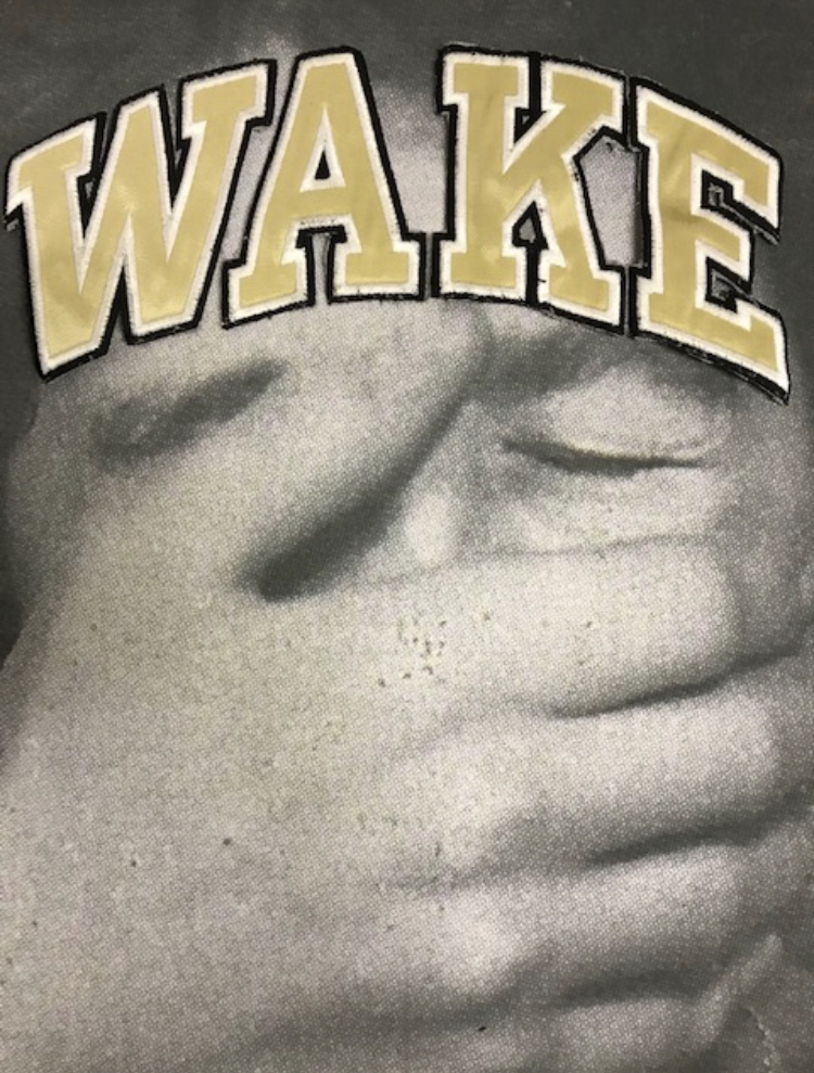 close up of a man's face with his hand placed across his mouth, the word wake printed across the top of the image