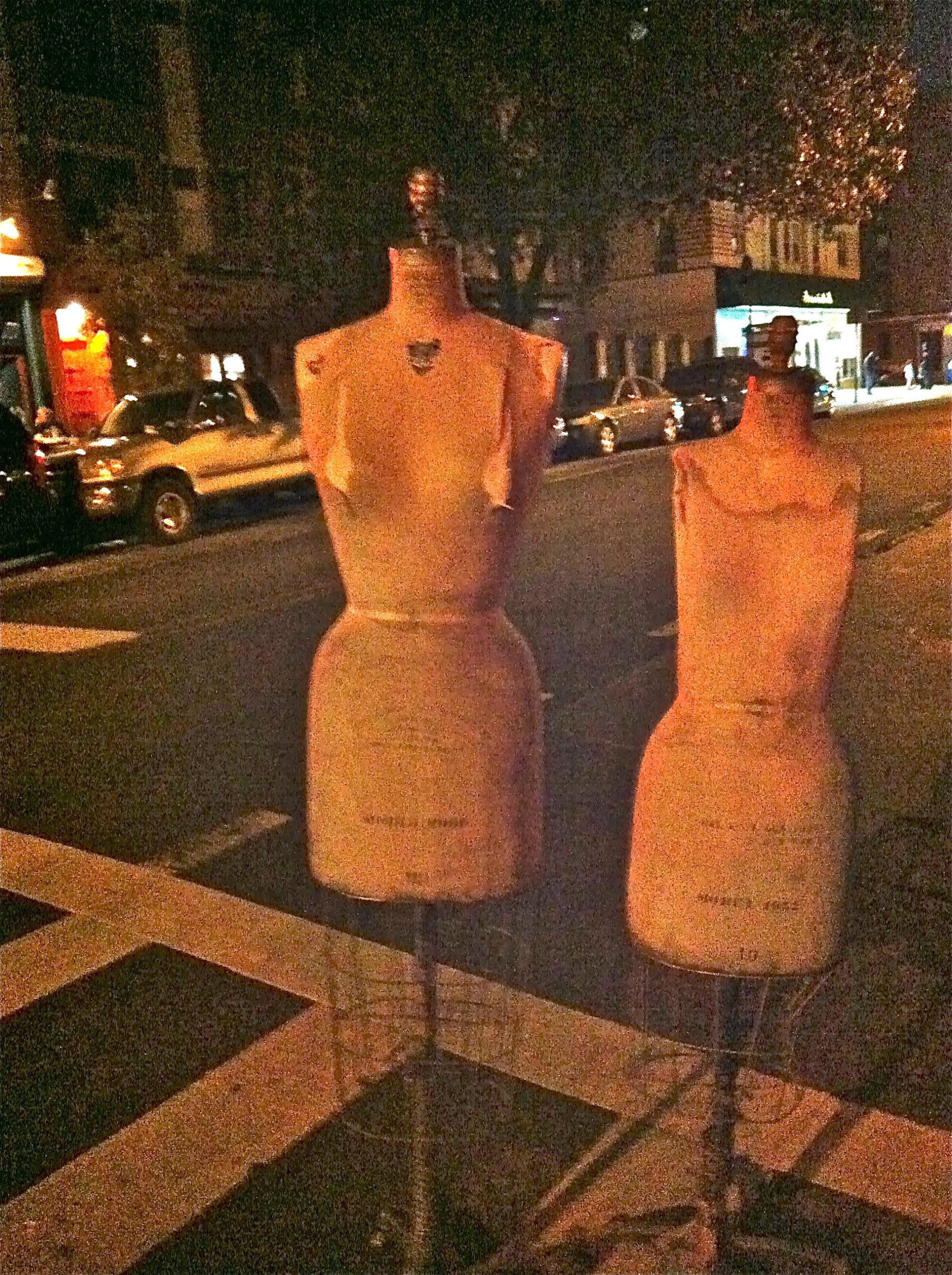 Two mannequins are positioned at the edge of a pedestrian road crossing in New York