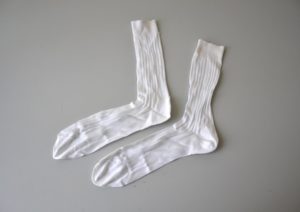 A photograph of two white socks, laid out on a blank, off-white background