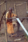 Guro weaver at work using a carved loom pulley