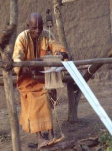 Guro weaver at work using a carved loom pulley