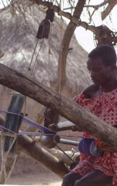Photograph of Boti bi Yuan, a Guro weaver, at work using a carved loom pulley, Côte D'Ivoire