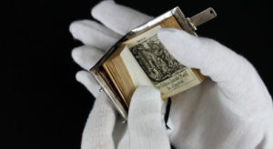 hands with white gloves holding a minature bible