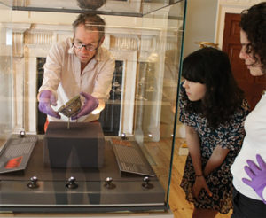 people looking at a museum display while object is being installed