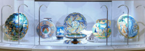set of decorated plates behind museum display