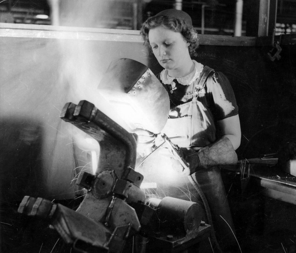 A young female factory worker arc welding a field gun in 1943