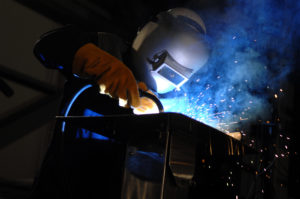 A Welder at work, with blue sparks and fumes
