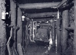 Mine tunnel with miner pushing loaded wagon