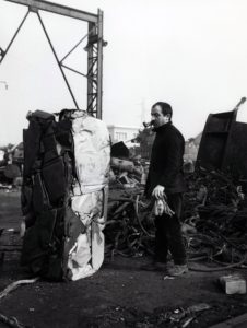 Artist César looking at crushed car in scrap yard