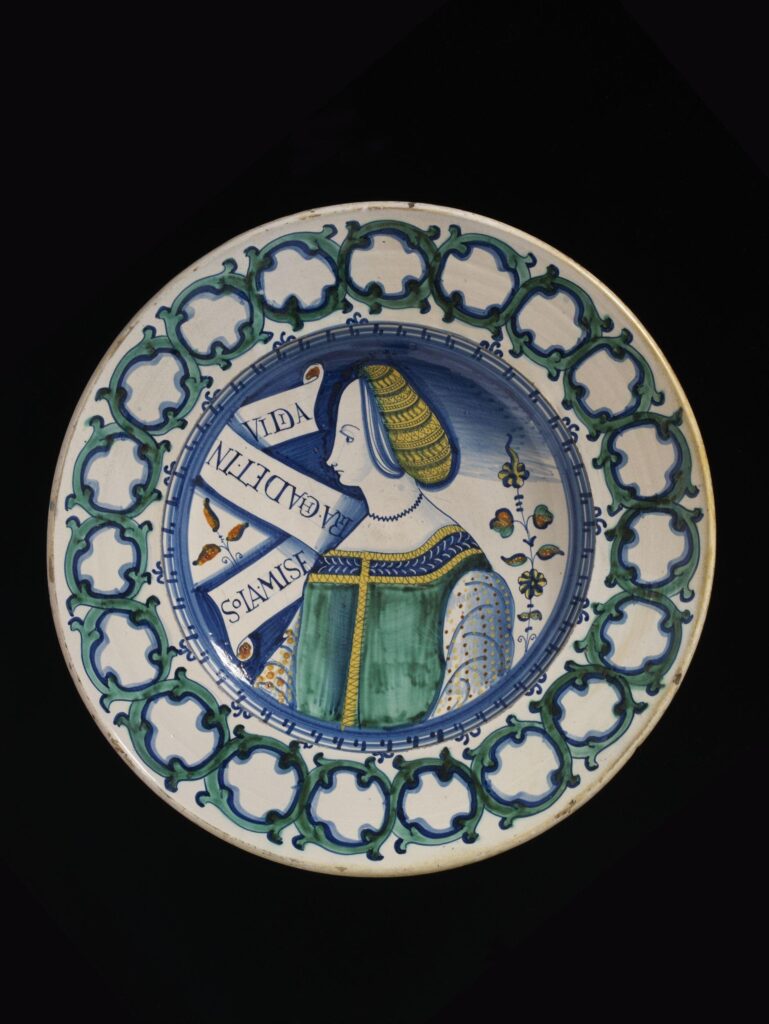 A ceramic dish painted with a figure and inscribed with a motto that says 'only misery is not envied' in Latin