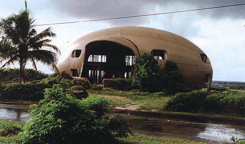 a big structure that looks like a capsule and has an open entrance, set in a natural landscape.