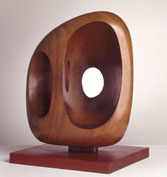 a squared wood sculpture with a hole in the centre and a cavity on the left side
