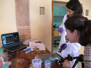 Amarilli Rava and a female student with a lab coat in a class looking at a computer screen