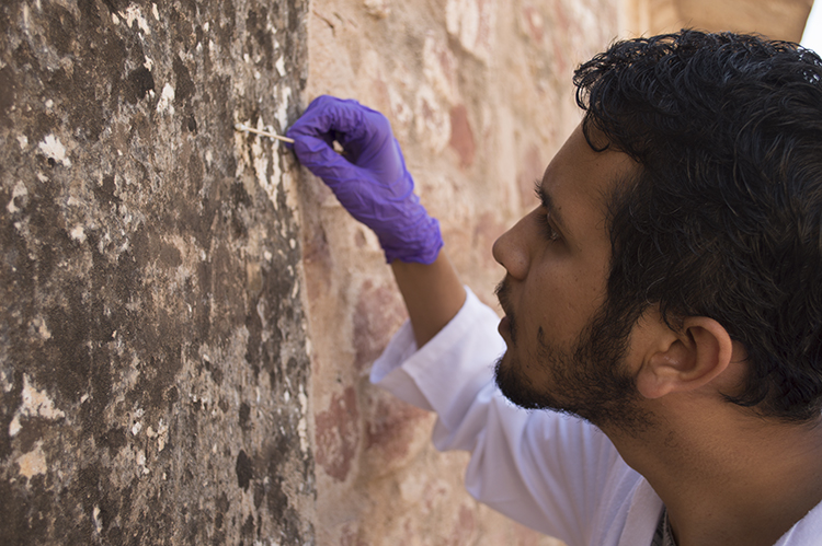One male student working on a wall painting wearing a glove