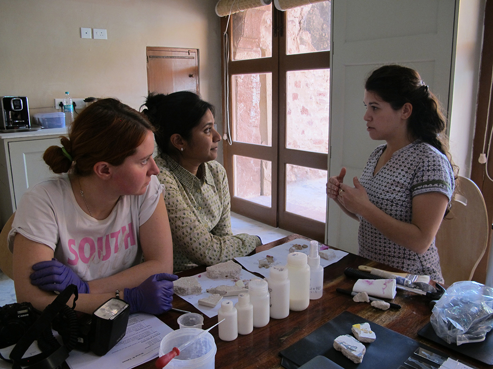 Three female students indoor looking at tools