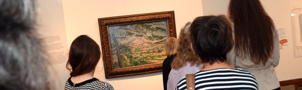 people standing in front of a cezanne painting