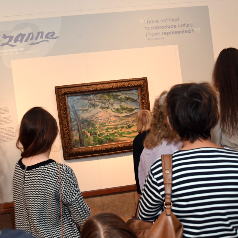 people standing in front of a cezanne painting