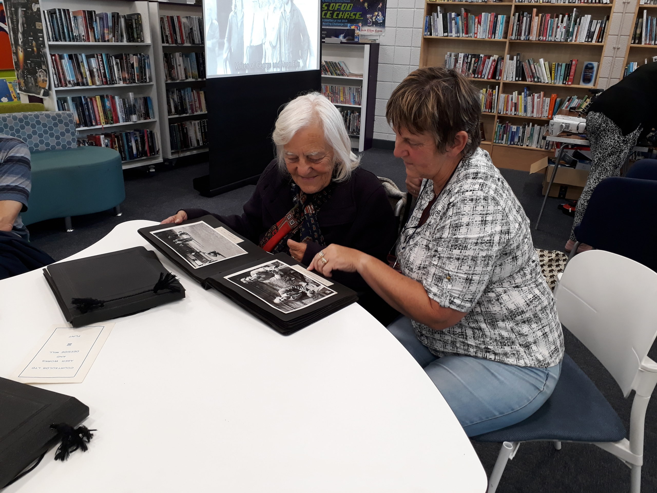 A volunteer discussing Courtauld memories with a visitor in library