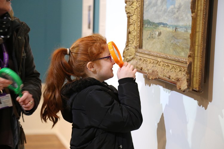 Girl viewing painting with magnifying glass
